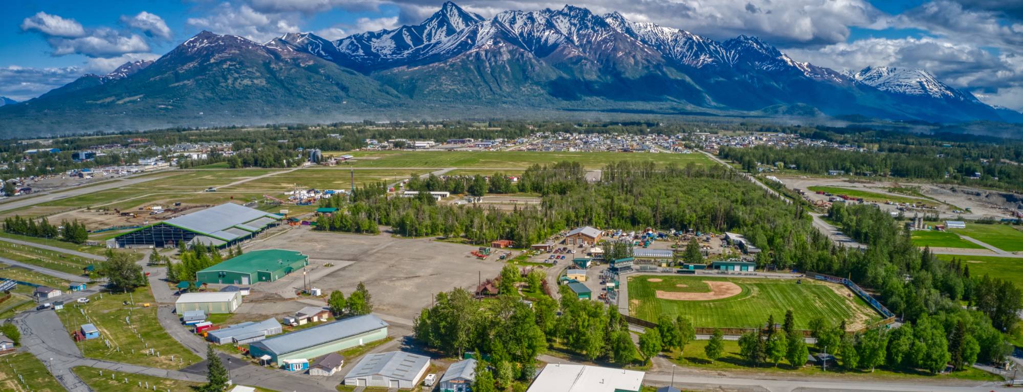 Aerial view of the Alaska State Fairgrounds in Palmer, with snow-capped Chugach peaks rising behind the town
