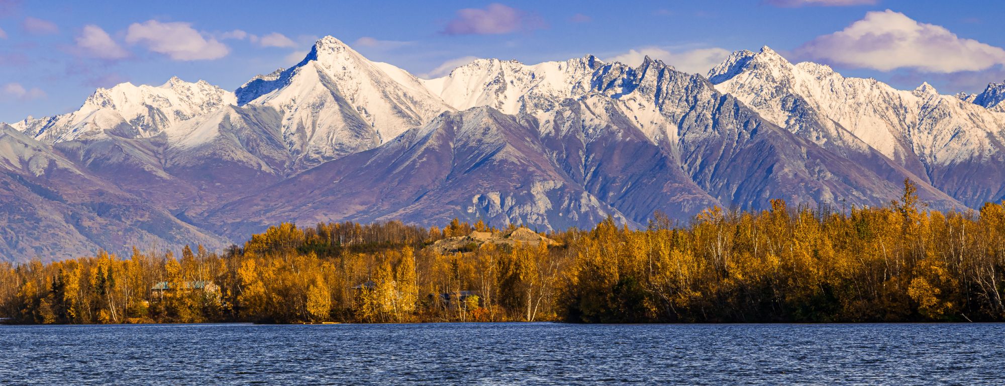 Snow-capped mountains above golden autumn birches and a lake in the Mat-Su Valley